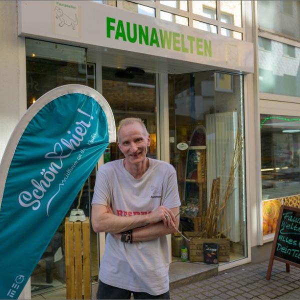 Ein fröhlich lächelnder Mann steht vor dem Geschäft Faunawelten. Neben ihm ist eine hellblaue Schön hier!-Fahne zu sehen | Foto: Walter Schernstein