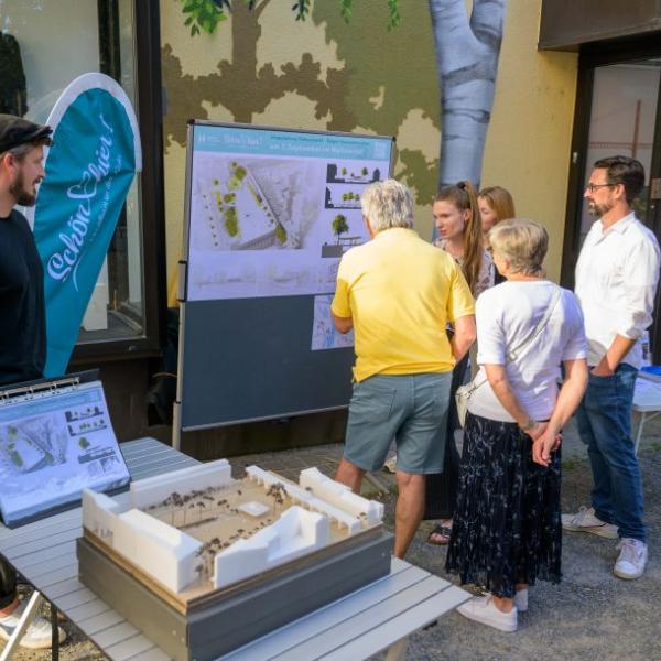 Einige Bürger*innen schauen sich die Planung des Rathausmarktplatzes auf einem Plakat an und lassen sich den Entwurf erläutern. | Foto: Walter Schernstein