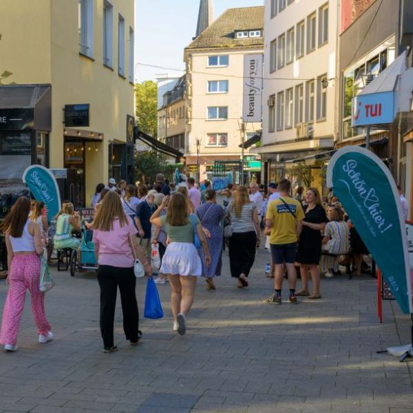 Passanten halten sich auf einer mit hellblauen Fahnen geschmückten Straße auf | Foto: Walter Schernstein