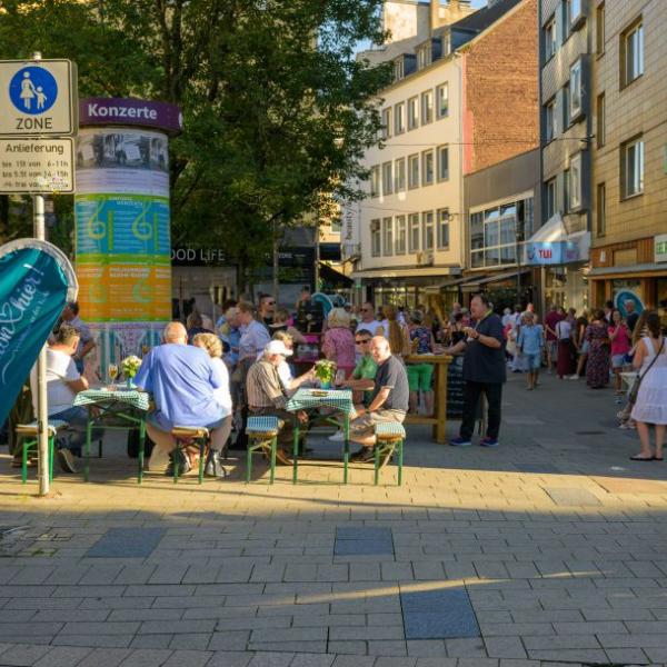 Passanten halten sich auf einer mit hellblauen Fahnen geschmückten Straße auf | Foto: Walter Schernstein