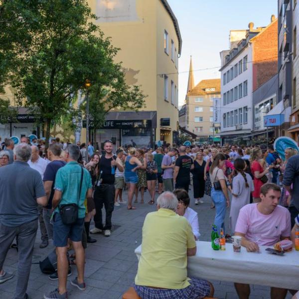 Passanten halten sich auf einer mit hellblauen Fahnen geschmückten Straße auf | Foto: Walter Schernstein