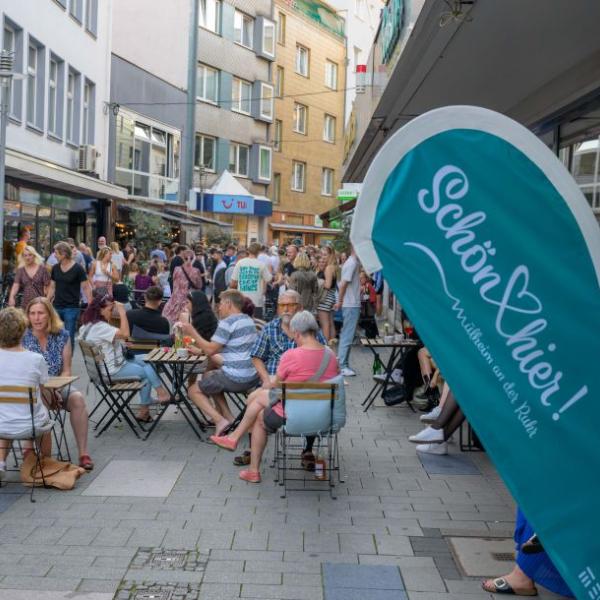 Passanten halten sich auf einer mit hellblauen Fahnen geschmückten Straße auf | Foto: Walter Schernstein