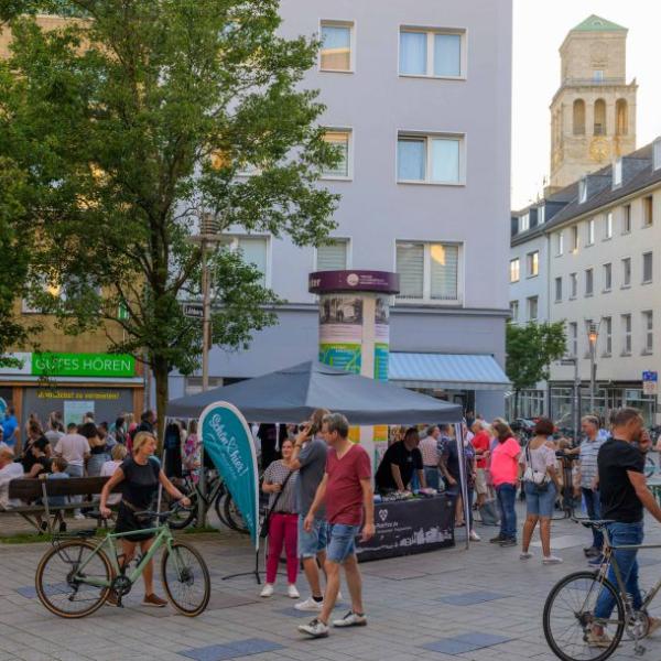 Passanten mit und ohne Fahrrad gehen durch einen mit hellblauer Schön hier!-Fahne geschmückten Straßenteil | Foto: Walter Schernstein